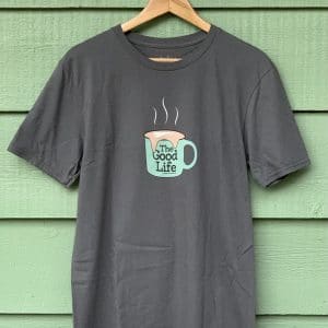 Front of Livin' Light's The Good Life coffee mug shirt with overflowing froth heart. The extra-large light green mug pops out from the dark gray shirt. The design illustrates the fulfillment God's abundant love for us.