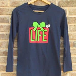 Front of Livin' Light's Christmas LIFE shirt. The design is on a navy, long-sleeved shirt and shows a gift wrapped in red with green ribbon for Christmas. The wrapping has a large word, "LIFE", on it in bright green. The tag on the gift says, "Love, God."