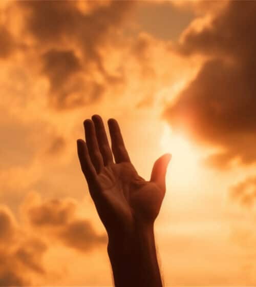 Praise God. Hand reaching up to an orange cloudy sky